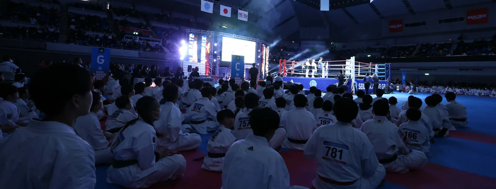 Children seated together watching the competition area at a national grand prix final.